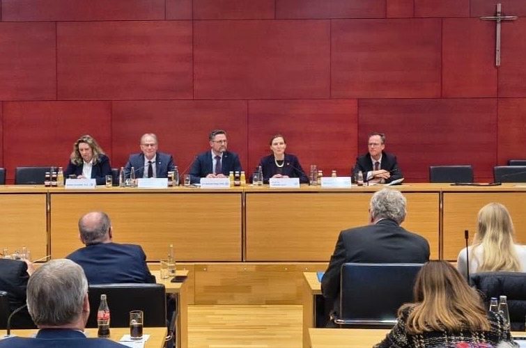 Sicherheitsgipfel Bayerischer Landtag Podiumsdiskussion mit fünf Personen, die an einem Tisch sitzen. Roter Hintergrund.