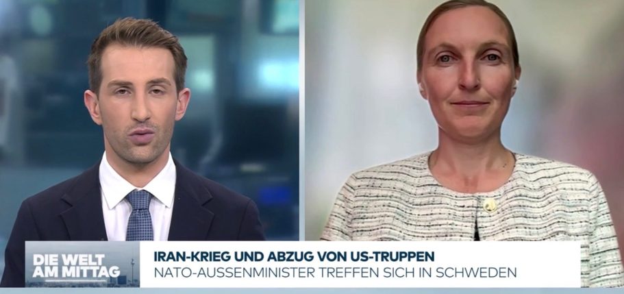 BR24 Interview Nachrichtenszene im Fernsehstudio mit US-Präsident Trump und Bundeskanzler Merz im Hintergrund.