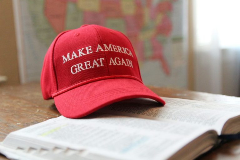 Rote Mütze mit dem Schriftzug "MAKE AMERICA GREAT AGAIN" auf einem aufgeschlagenen Buch.