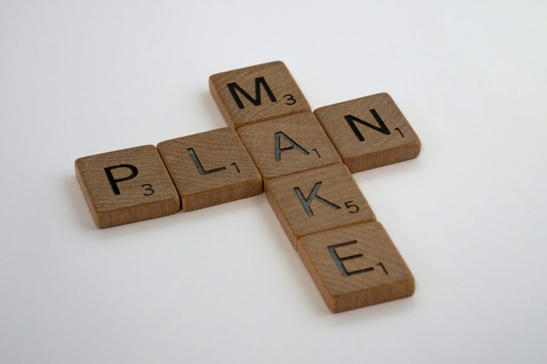 Scrabble-Bausteine mit den Wörtern "MAKE" und "PLAN".