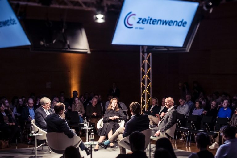 Zeitwende on Tour Diskussion auf einer Bühne mit mehreren Sprechern und Publikum im Hintergrund.