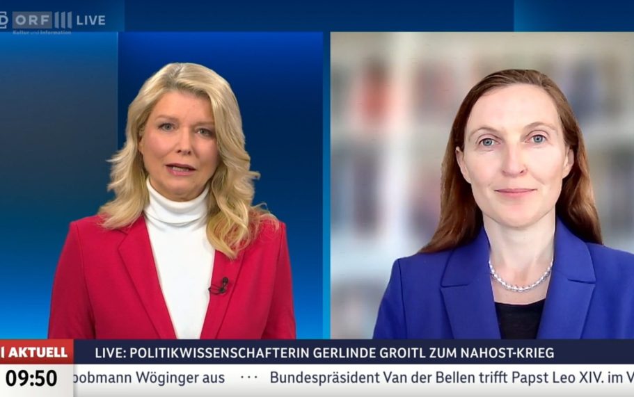 BR24 Interview Nachrichtenszene im Fernsehstudio mit US-Präsident Trump und Bundeskanzler Merz im Hintergrund.