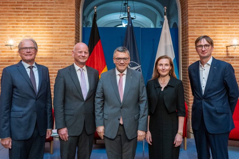Podiumsdiskussion Prinz-Carl-Palais Mai 2025 Fünf Personen stehen vor einem Wand mit Flaggen und einer offiziellen Gestaltung.