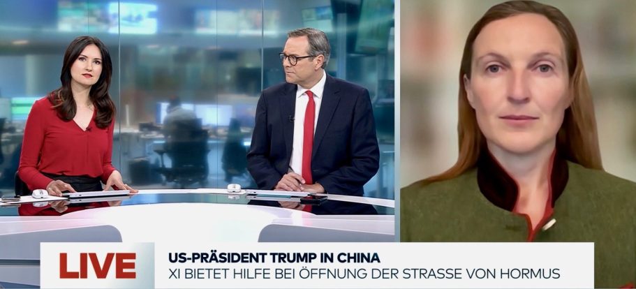 BR24 Interview Nachrichtenszene im Fernsehstudio mit US-Präsident Trump und Bundeskanzler Merz im Hintergrund.