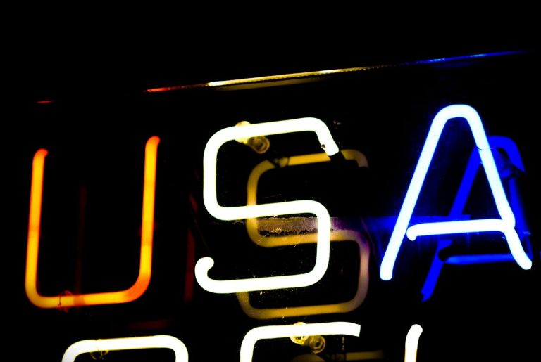 Leuchtende Neonbuchstaben "USA" auf schwarzem Hintergrund.