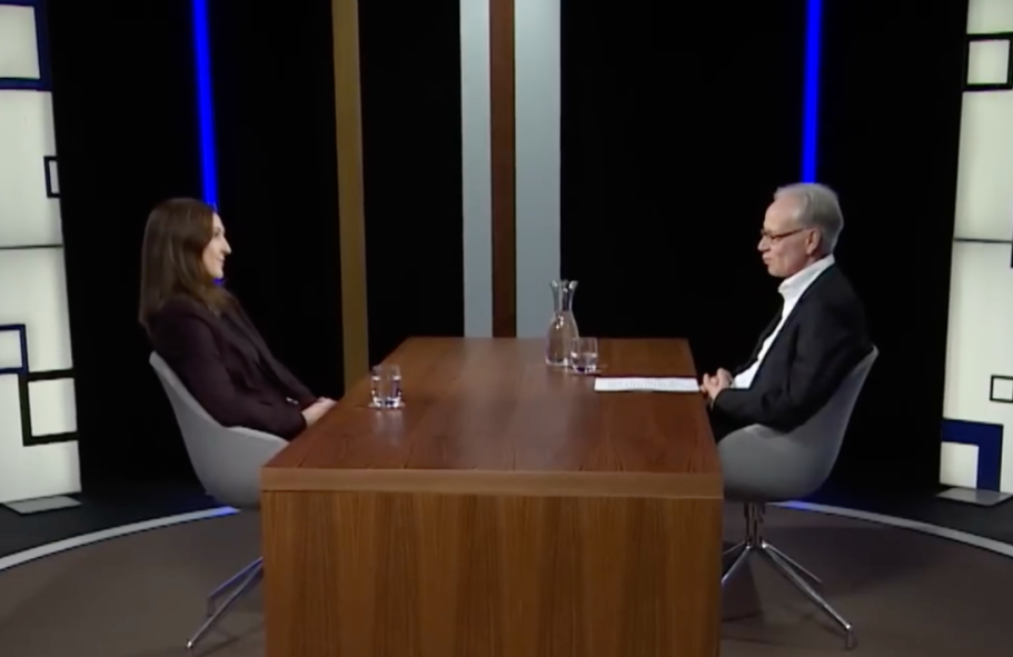 Interview mit BR Rundschau zum Alaska-Friedensgipfel Frau vor Bücherregal
