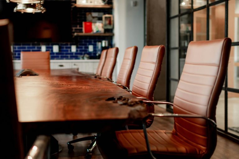 Ein Konferenzraum mit einem langen Holztisch und Lederstühlen.