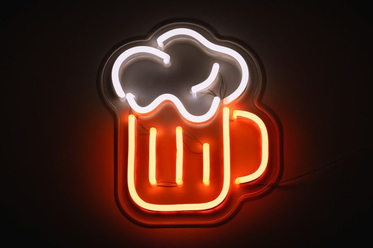 Neon-Schild eines Bierkrugs mit Schaum auf dem Glas, leuchtend in Orange und Weiß.